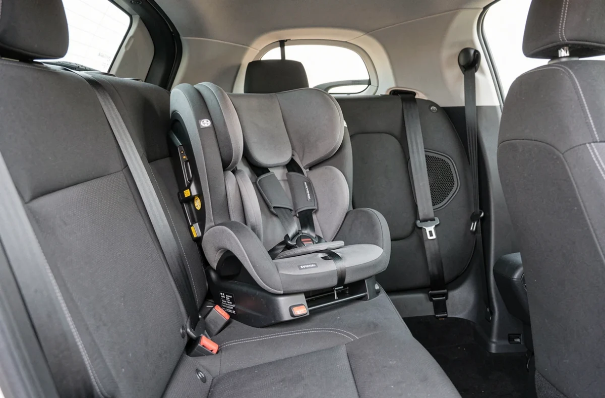 Siège auto compact installé dans l'habitacle étroit d'une voiture citadine, montrant l'espace réduit et les fixations ISOFIX